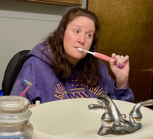 Jennifer brushing her teeth at the bathroom sink, looking thoughtful and slightly anxious before a routine dentist appointment