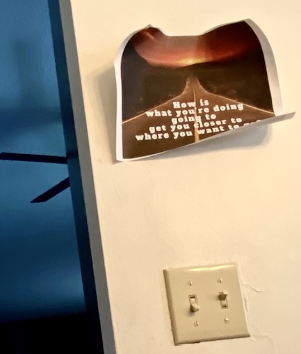 Handwritten motivational note on a wall asking how current actions align with long-term goals in a home setting