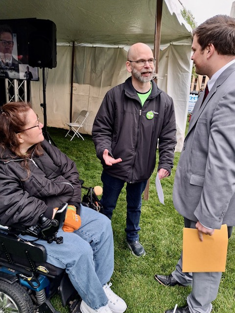 Dan and Jennifer Digmann speaking with Adam Lawrence from Senator Roger Hauck’s office during Older Michiganians Day 2026 about caregiving, accessibility, and independent living.