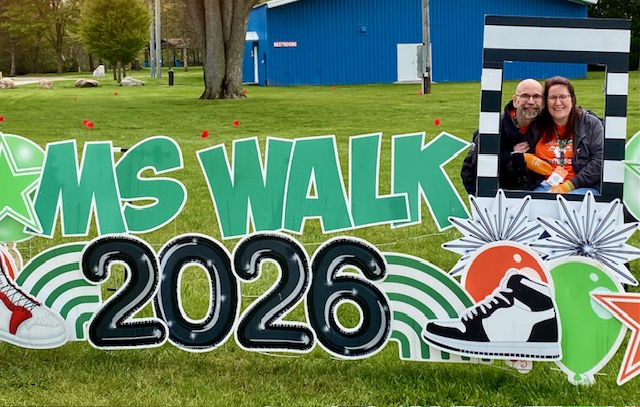 Dan and Jennifer Digmann smile together behind the Walk MS 2026 sign during the National MS Society event in Frankenmuth, Michigan.”